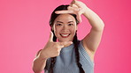 Happy, frame and face of asian woman in studio for positive, creative and posing. Focus, emoji and camera sign with girl and hand gestures on pink background for photography, satisfaction and picture