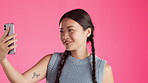 Asian woman, face and smile for selfie, vlog or profile picture against a pink studio background. Happy Japanese female smiling for photo with facial expression and hand signs for social media post