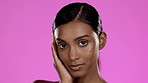 Beauty, studio and Indian woman with hand on face for skincare, cosmetics and isolated on pink background. Natural makeup, dermatology and skin care model posing with luxury spa or salon detox facial