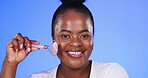 Black woman, beauty and facial roller portrait for skincare on  blue background in studio with glow. Happy African female model person for skin massage with cosmetics, dermatology and face makeup