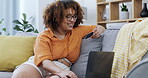 Couch, laptop and woman with credit card, happy for online shopping, ecommerce or fintech easy payment at home. Black person typing bank information on her computer for finance transaction on a sofa