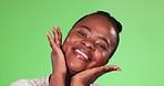 Black woman, beauty and hands on face for skincare on a green background in studio with skin glow. Happy African female model person laugh or smile for cosmetics, dermatology and facial makeup shine