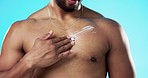 Skincare, applying and man with cream on his chest isolated on a blue background in a studio. Moisturizing, sexy and male model with sunscreen, lotion or moisturizer on his body for grooming