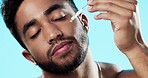 Skincare, health and man with face serum in a studio with a beauty, grooming and face routine. Wellness, cosmetic and male model with a facial oil pipette for a skin treatment by a blue background.