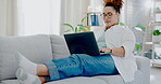 Woman relax on couch with laptop for internet, online streaming or freelance networking in her apartment. Work from home, break and happy biracial person on sofa in living room working on computer