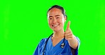 Asian woman, doctor and thermometer with thumbs up on green screen for healthcare success against studio background. Portrait of nurse with infrared scanner showing thumb emoji, yes or like on mockup