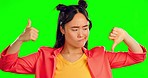 Confused, review and a woman on a green screen with a thumbs up or down isolated on a studio background. Decision, choice and portrait of an Asian girl with doubt about hand gesture feedback