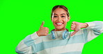 Review, decision and face of a woman with a thumbs up or down on a isolated on green screen. Choice, confused and portrait of a girl with difficult feedback, hand gesture and promotion on a backdrop