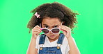 Child, portrait and sunglasses with an attitude on green screen background peeking over glasses. Black girl kid in studio for comic, funny and facial expression or mood while angry or curious
