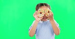 Donut on eyes, smile and child on green background with cake over face for funny, meme and comic. Food, excited kid and isolated happy girl with sweets, dessert treats and sugar doughnuts in studio
