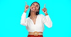 Excited, happy and woman pointing up at mockup showing deal, sale and branding isolated in a studio blue background. Smile, fashion and portrait of Indian female show product placement or logo