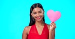 Smile, woman and heart paper sign for Valentines Day, studio care and emoji love icon, symbol or poster. Portrait girl, playful female or happy Indian person with romantic support on blue background
