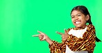 Showing, product placement and face of a child on a green screen isolated on a studio background. Laughing, happy and a portrait of a young girl pointing to mockup space for branding and advertising