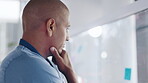 Doctor, man and thinking in schedule planning, healthcare or tasks on glass board at hospital. Serious thoughtful male medical expert in project plan, sticky note or brainstorming strategy at clinic