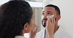 Couple, eye patches and smile for skincare beauty or cosmetics in morning bathroom routine together at home. Happy man with woman applying cosmetic product, face mask or patch for healthy wellness
