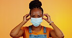 Covid face mask, studio black woman and thumbs up for bacteria safety, corona virus compliance or security policy. Portrait, emoji icon gesture or female with pandemic protection on orange background