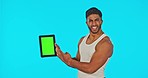 Green screen, digital tablet and face of man pointing in studio for fitness, advertising and hand gesture on blue background. Portrait, mockup and man with app for health, exercise and gym progress