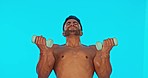 Fitness, weights and man doing a workout in a studio for health, wellness and arm strength. Sports, motivation and strong male athlete model doing an intense exercise isolated by a blue background.