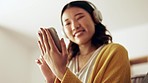 Woman hands, headphones and phone in a living room with happiness from music and texting. Home, lounge sofa and smile of a Asian female and gen z student feeling relax from audio and web podcast