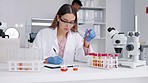 Scientist, woman and blood sample analysis in a laboratory for medical research. Science, dna testing and lab project check with a female pharma and hospital employee with microscope and test tube