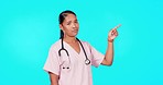Woman, doctor and point in studio for mockup, healthcare decision and menu by blue background. Young female medic, pointing or portrait for presentation, mock up space and medical advice promotion