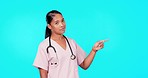 Woman, doctor and pointing in studio for mockup, healthcare decision and menu by blue background. Young female medic, point and portrait for presentation with mock up space for medical promotion