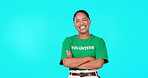 Volunteer, charity and a woman on a blue background in studio standing arms crossed for community service. Portrait, happy and smile with a female activist volunteering for social welfare or relief