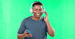 Music headphones, phone and black man dancing on green screen in studio isolated on a background. Cellphone, dance and happiness of African person streaming or listening to podcast, radio or audio.