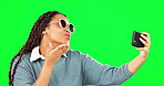 Selfie, sunglasses and kiss with a woman on a green screen background in studio for a profile picture. Photograph, fashion and style with a cool young female posing for social media status update