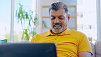 Senior man, laptop and smile in home living room, social media or typing online. Computer, retirement and happiness of male person with technology for streaming movie, film or video on lounge sofa.