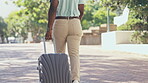 Man, walking and travel with luggage outdoor on city street for holiday, adventure or business. Back of black male with suitcase and legs to walk to urban destination for vacation, journey or freedom