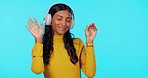 Woman, music and headphones with dance in studio for listening, relax and sound for peace of mind. Gen z girl, streaming audio and happy student with sexy dancing to internet radio by blue background