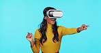 VR, interactive and a woman with glasses for a metaverse isolated on a blue background in studio. Happy, futuristic and a girl in a 3d virtual reality, playing games and feeling the experience