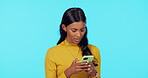 Phone, internet and woman chatting on a social media app online and isolated in a blue studio background. Young, mobile and female texting a message on a cellphone and browsing the web or website