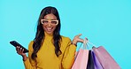 Happy woman, phone and shopping bags in studio for purchase, sale or discount against a blue background. Portrait of female shopper smile with smartphone for fashion, buying or social media on mockup