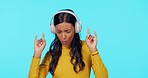 Woman, music and headphones with dancing in studio, relax and listen to rock n roll band on web. Gen z girl, streaming subscription and audio for student, dancer and internet radio by blue background
