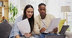 Laptop, couple talking and documents for finance, taxes or savings on sofa in home. Interracial, paperwork and black man and woman with computer for planning budget, insurance or financial bills.