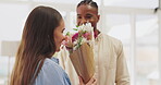 Surprise, flowers and couple hug in home to celebrate anniversary, bonding and romance. Floral bouquet, interracial and happy black man and woman embrace or cuddle with gift or present for love.