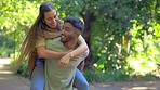 Love, jump and piggy back for couple in park walking in garden and bonding on summer weekend together. Interracial happiness, man carrying happy woman with smile and laugh on romantic date in nature.