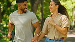 Love, happy and interracial couple running in a park together on a date in nature and bonding in happiness outdoors. People, man and woman playing enjoying freedom and romance in a forest