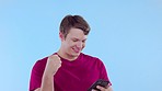 Winner, celebration and man with phone on blue background with achievement, victory and cheering. Success mockup, excited and male on smartphone winning online competition, bonus and prize in studio