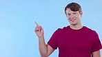 Happy, mockup and face of a man pointing isolated on a blue background in a studio. Smile, advertising and portrait of a guy with a gesture to mock up space for branding, marketing or promotion