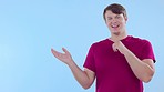 Face, space and man pointing, mockup and decision against a blue studio background. Portrait, happy male and young person with smile, excited and opportunity with sales, discount or brand development
