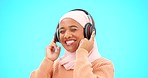 Happy woman, headphones and dancing isolated on blue background listening to music for celebration and singing . Funny, dance and muslim, gen z or hijab person with streaming technology in studio