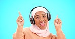 Headphones, dancing and happy woman isolated on blue background listening to music in celebration and winning. Winner, dance and muslim or hijab person face with audio streaming technology in studio