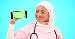 Phone, green screen and doctor woman isolated on blue background for healthcare tracking marker and mockup space. Face of nurse or muslim person with medical mobile app for advertising in studio