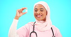 Nurse, medical and vaccine with a muslim woman on a blue background in studio for treatment. Healthcare, product and insurance with a young female medicine professional holding a glass bottle