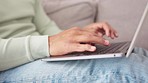 Closeup, man hands and laptop on sofa for typing, email communication or seo for social media. Male, computer and work from home for web design, internet and website development in living room