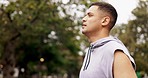 Fitness, runner and man drinking water in a park after running, exercise and training in nature. Sports, hydration and thirsty athletic male in a forest for break during workout, performance and run