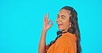 Smile, wink and okay hand gesture, woman on studio backdrop with mockup and freedom and positive opinion. Happy gen z model, ok sign and girl with creative lifestyle, agreement and blue background.